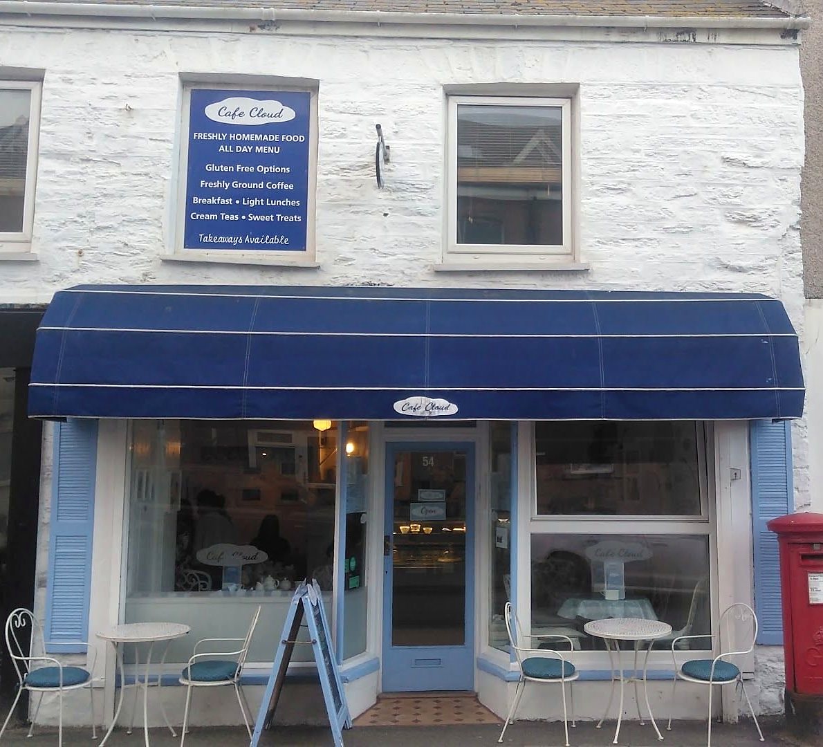 Cafe Cloud on Fore Street: white-painted front, navy awning, blue shutters, bistro chairs and a red post box by the door